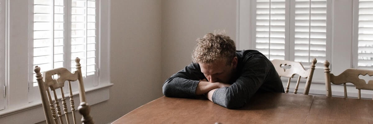 Man Slumping On Table Going Through Emotional Trauma