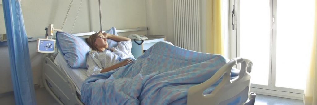 Woman lying in hospital bed with pre existing condition