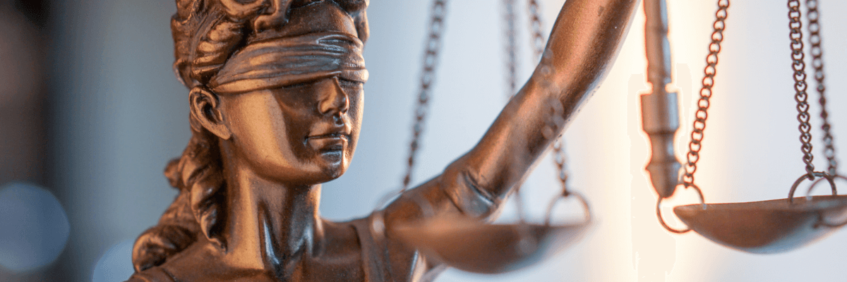 a bronze lady of law stature holding up a scales against a bright background